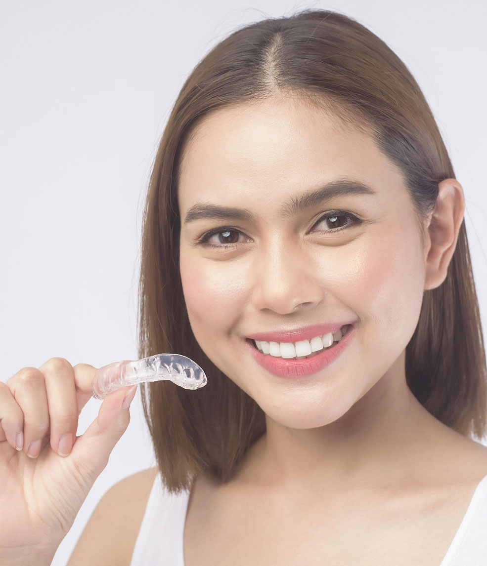 Smiling young woman holding Invisalign aligners